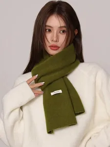 Close-up detail of a premium green 100% Australian wool knitted scarf worn by a model