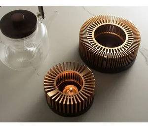 Macro shot of gold metallic ribbed tea warmer stand with lit candle and glass teapot