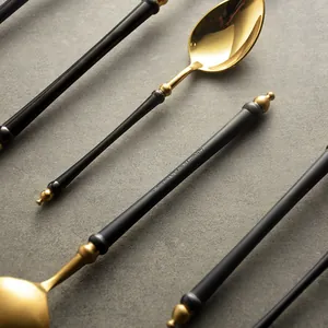 Elegant black and gold 304 stainless steel spoons on a grey stone texture background