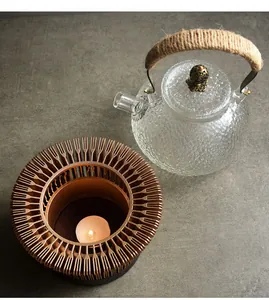 Close-up view of hollowed tea warmer base with textured glass teapot and candle