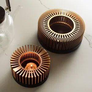 Modern golden metal tea warmer with wooden base and lit candle