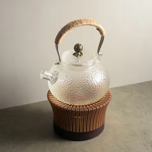 Elegant hammered glass teapot with hemp rope handle on a hollow wooden candle warmer