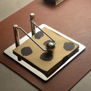 Modern stainless steel napkin holder with weighted ball arm on leather mat