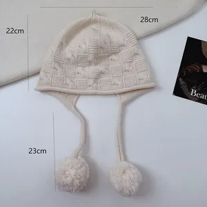 Detail view of a cream wool knit beanie with pom-pom ear flaps and dimensions shown.