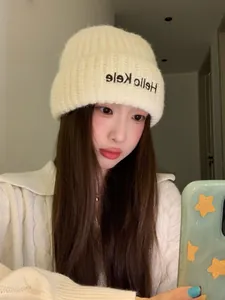 Close-up of soft beige winter knitted beanie hat with Hello Kele embroidery on an Asian model