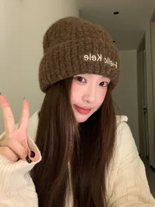 Close-up of a warm brown knitted beanie hat with Hello Kele embroidery on an Asian model