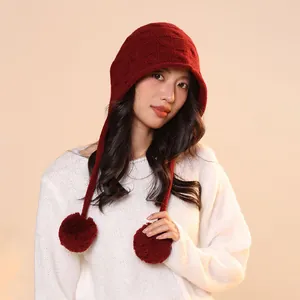 Detailed view of a dark red pure wool pumpkin style knitted hat with soft pom-poms