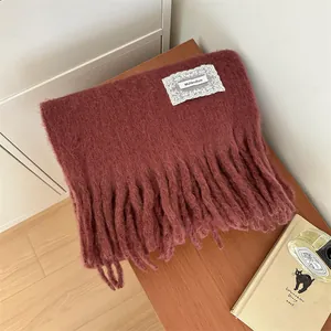 Detail of burgundy mohair knit scarf with elegant lace patch and soft tassels.