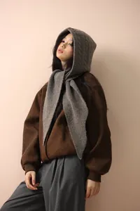 Vista dettagliata di una sciarpa con cappuccio Balaclava in maglia grigia su un modello.