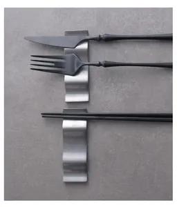 Top-down view of wavy stainless steel cutlery rest holding black knife and fork