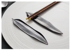 Vue détaillée des repose-baguettes noirs en forme de feuille de saule sur une assiette blanche