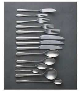Detailed view of vintage matte stainless steel cutlery set on grey stone background