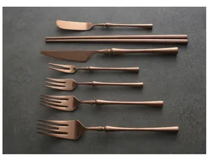 Detail of retro rose gold stainless steel cutlery set with slender handles on stone background
