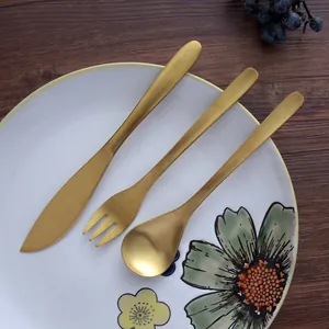 Retro golden stainless steel cutlery set with willow leaf design on white ceramic plate