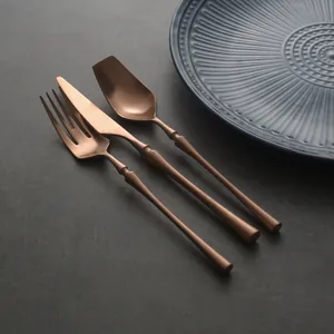 Vintage rose gold stainless steel cutlery set with slim handles on dark background