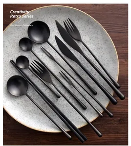 Elegant black matte stainless steel cutlery set arranged on a speckled ceramic plate