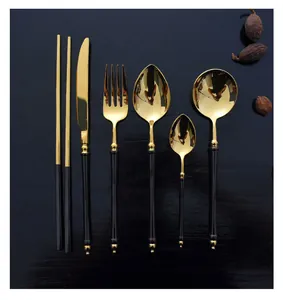 Detail of gold and black 304 stainless steel flatware set on dark wood