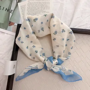 Close-up of vintage floral square scarf with delicate blue flowers on beige tray