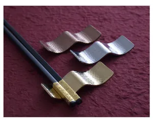 Close-up of hammered wave-shaped stainless steel chopstick rests in three metallic colors.