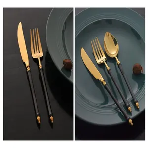 Detail view of elegant black and gold stainless steel cutlery set with bamboo style handles