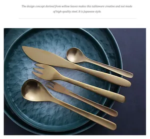 Close-up of elegant gold willow leaf style stainless steel cutlery on textured teal plates