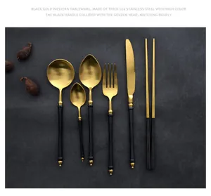 Close-up detail of black and gold 304 stainless steel cutlery set on dark background.