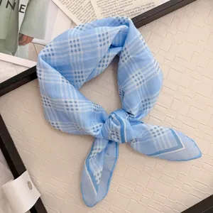 Detail of a light blue and white checkered cotton-linen square scarf tied in a knot