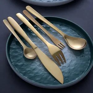 Premium 5-piece gold 304 stainless steel cutlery set on textured green ceramic plate.