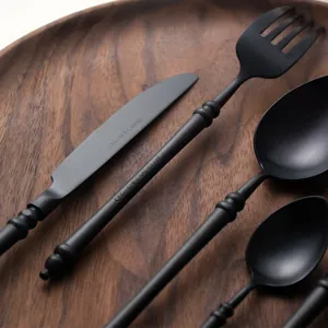 Matte black 18/8 stainless steel cutlery set with bamboo inspired handles on wood.