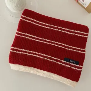 Close-up detail of a vintage red and white striped knit scarf featuring a woven logo label