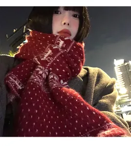 Dettaglio di una calda sciarpa rossa in maglia con ricami a forma di fiocchi di neve.