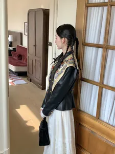 Close-up of floral printed silk scarf and black velvet bag styled with leather jacket and lace dress