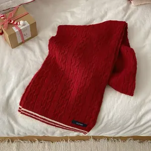 Detail of vintage red cable knit scarf with white stripes and elegant logo label
