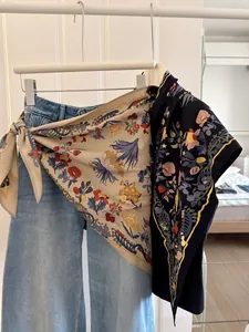 Detail of floral triangular silk scarf styled as a decorative waist wrap on denim jeans