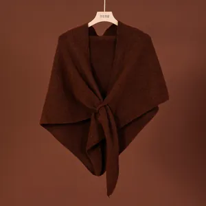 Macro view of a brown wool blend knitted shawl with an elegant front cross-knot design