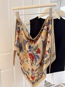 Detail view of floral printed silk triangle scarf with vintage patterns on a hanger.