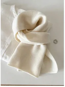 Close-up detail of a soft cream 100% wool knit scarf styled on a white linen shirt