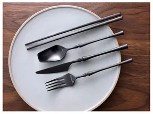 Top view of premium black brushed stainless steel cutlery set on a grey ceramic plate.