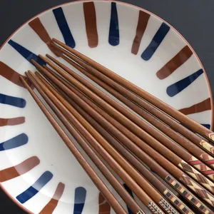 Japanese style wooden chopsticks with geometric patterned ends on ceramic plate