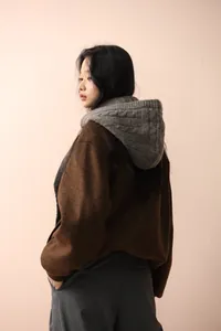 Vista posteriore dettagliata di una sciarpa passamontagna grigia su modella con cappotto.