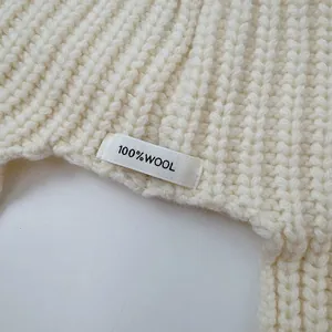 Detailed macro view of 100% wool label on premium cream knitted balaclava winter hat