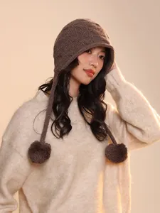 Detailed view of handmade wool elf pumpkin beanie with pom-poms worn by a female model