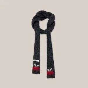 Detailed view of minimalist dark grey skinny knit scarf with red cherry pattern