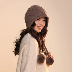 Detailed view of a brown wool pumpkin style beanie hat with decorative pompom accents