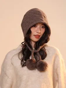 Detailed view of a brown wool pumpkin style beanie featuring soft pom-poms and cable knit