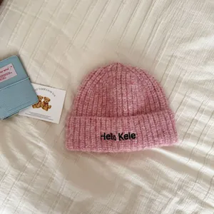 Macro view showing the soft texture and 'Hello Kele' embroidery on pink beanie