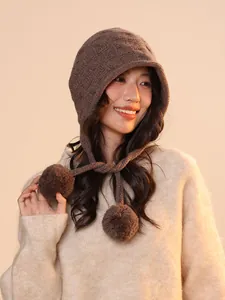 Close-up of a stylish brown pure wool knitted elf hat with cute hanging pom-pom details