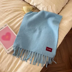 Detailansicht eines hellblauen Wollschals mit Fransen und Markenlabel