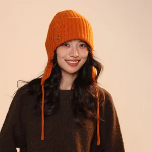 Close-up of a warm orange 100% wool knitted balaclava with earflaps and long ties