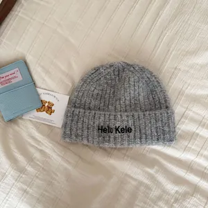Detail showing the soft texture and Hello Kele embroidery of the gray knitted beanie hat
